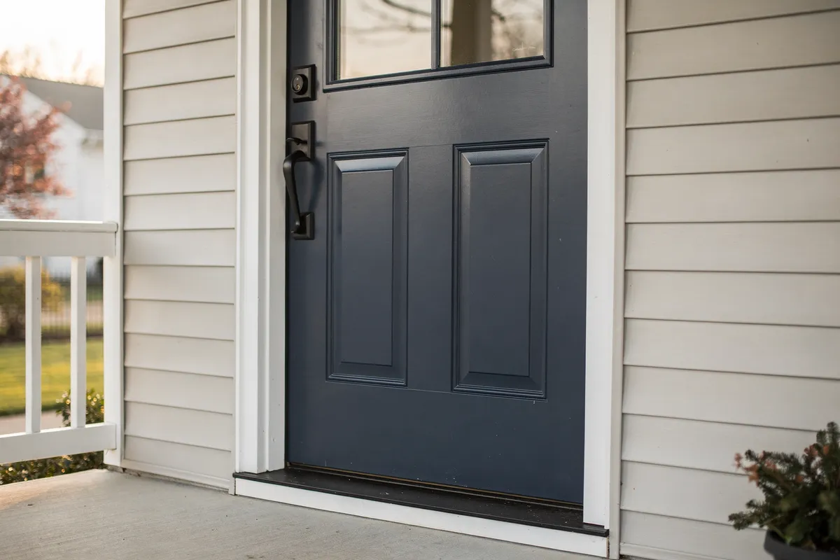 Puerta de entrada estilo craftsman azul marino recién instalada con herrajes nuevos